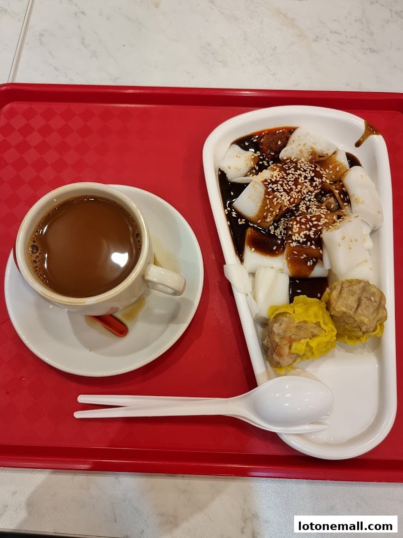 A cup of coffee and a plate of dim sum with rice noodle rolls on a red tray.