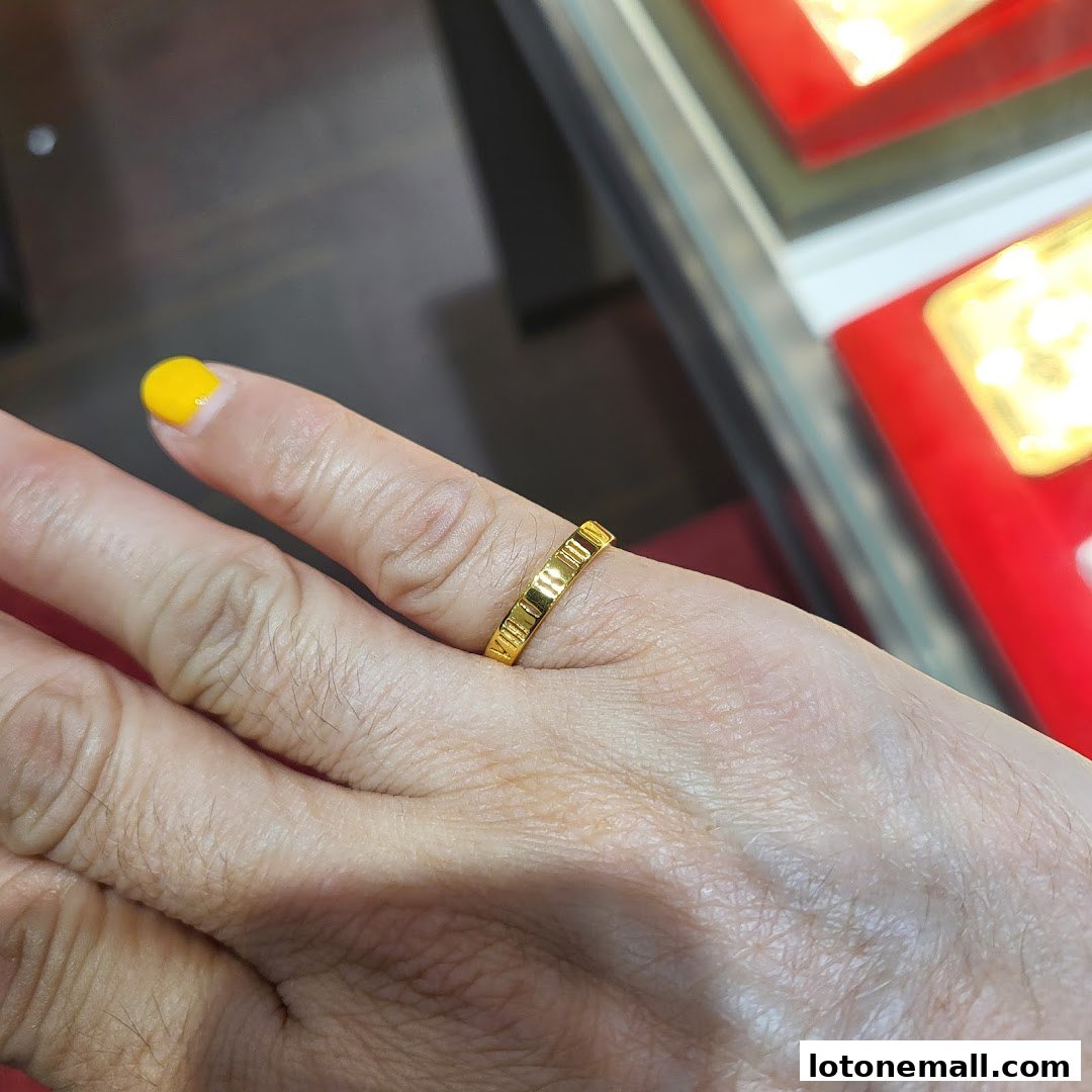 A close-up shot of a hand wearing a gold ring with a textured design.