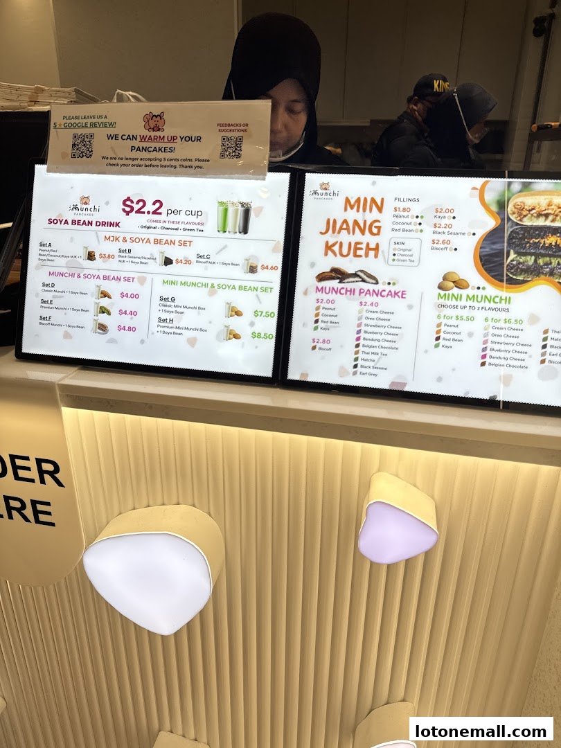 A digital menu board displaying pancakes, mini munchis, and soya bean drinks with prices.