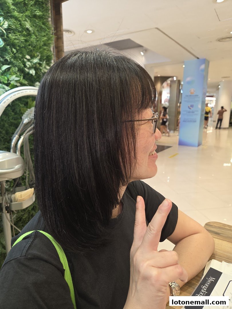 A woman with dark hair smiles and flashes a peace sign at Myeongdong Hair Studio.