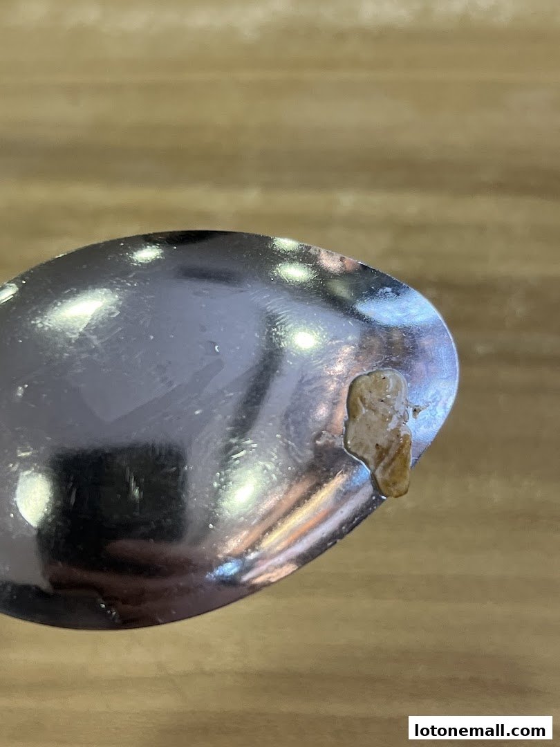 A close-up shot of a spoon with a small amount of food residue on its edge.