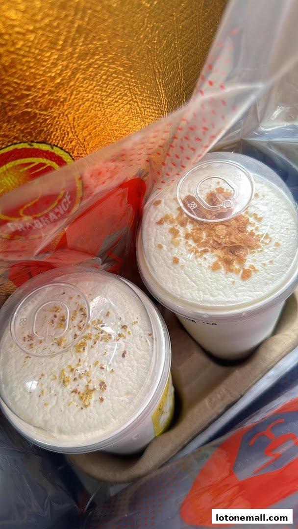 Two creamy milk tea drinks with toppings in a takeaway bag.