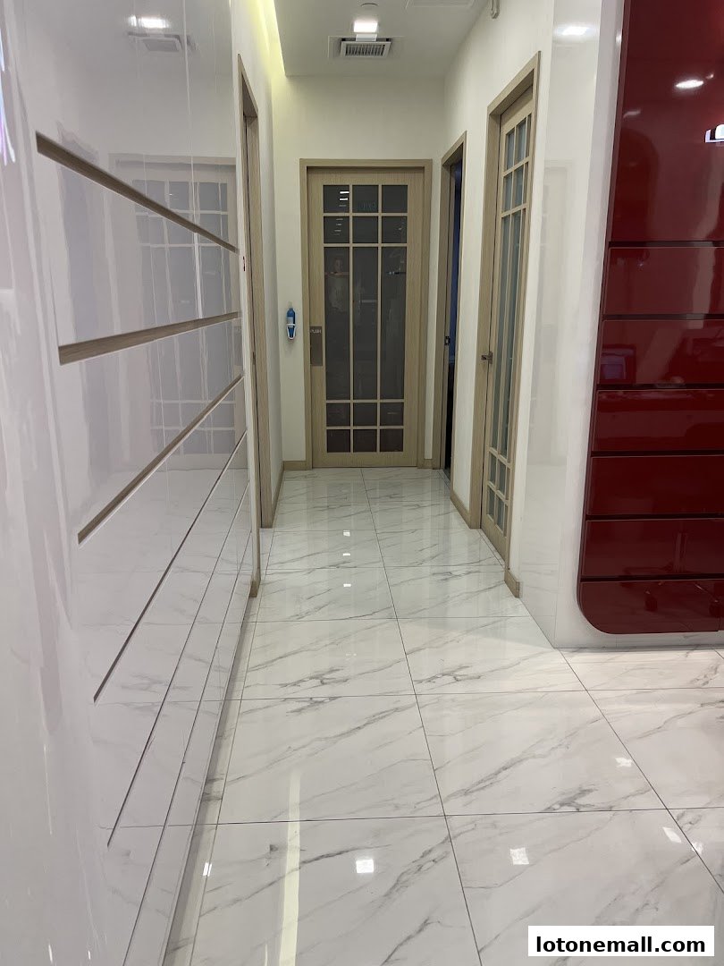 A clean, modern hallway with marble flooring and doors leading to treatment rooms.