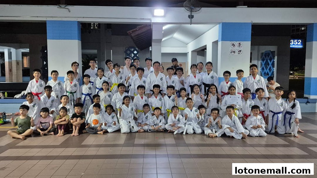 A large group of children and adults in martial arts uniforms pose for a photo.