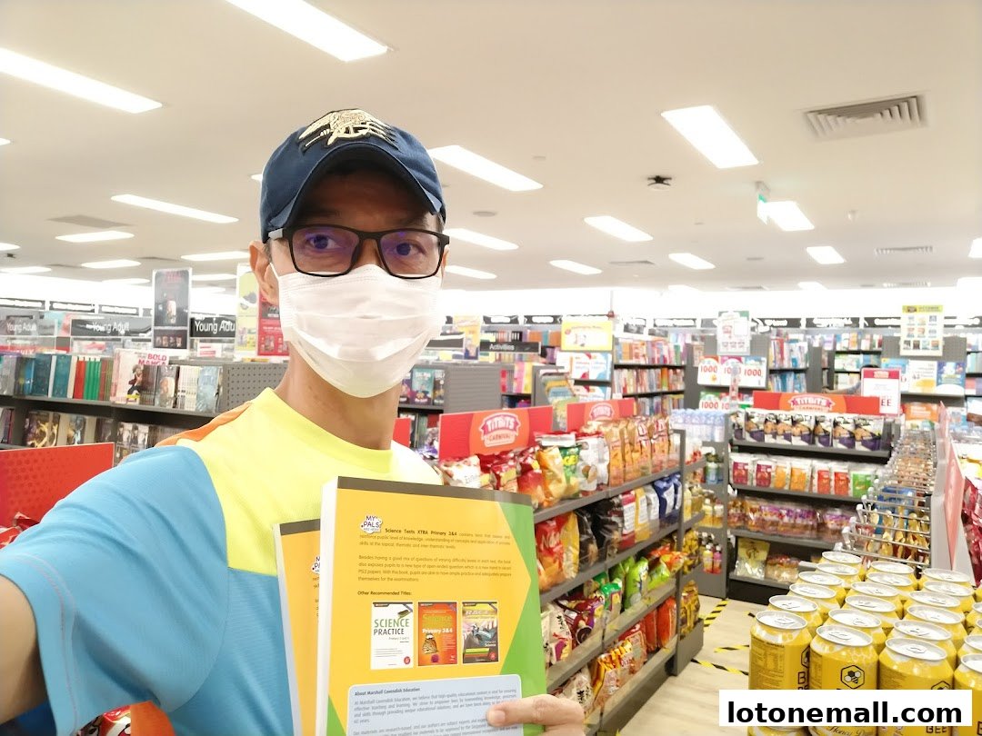 A person wearing a mask and holding books in a well-stocked bookstore.