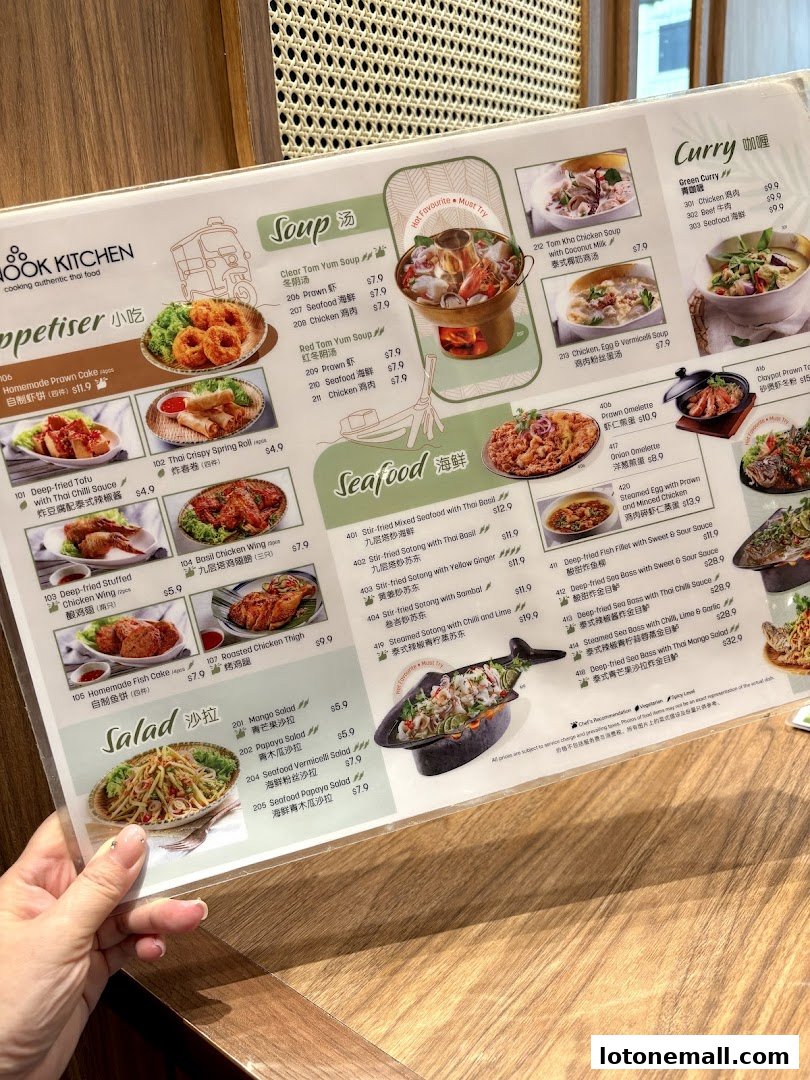A person holding a menu from Sanook Kitchen, showcasing various Thai dishes with images and prices.