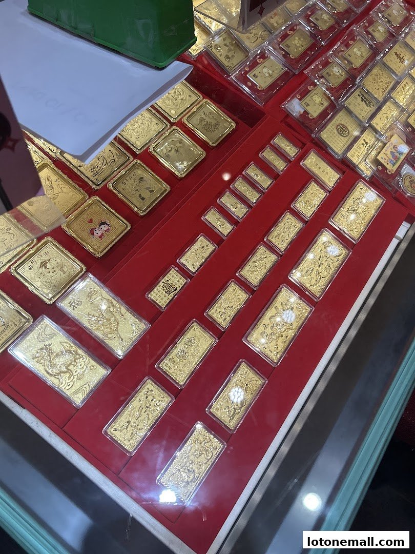A display case filled with various gold bars and ingots, many featuring intricate designs.
