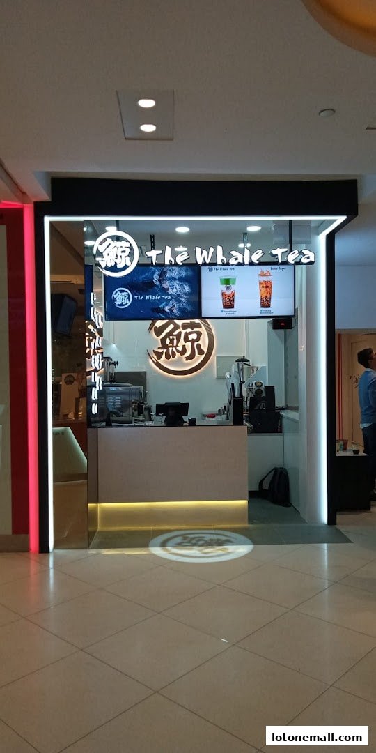 The Whale Tea shop front with illuminated signage and a display of bubble tea.