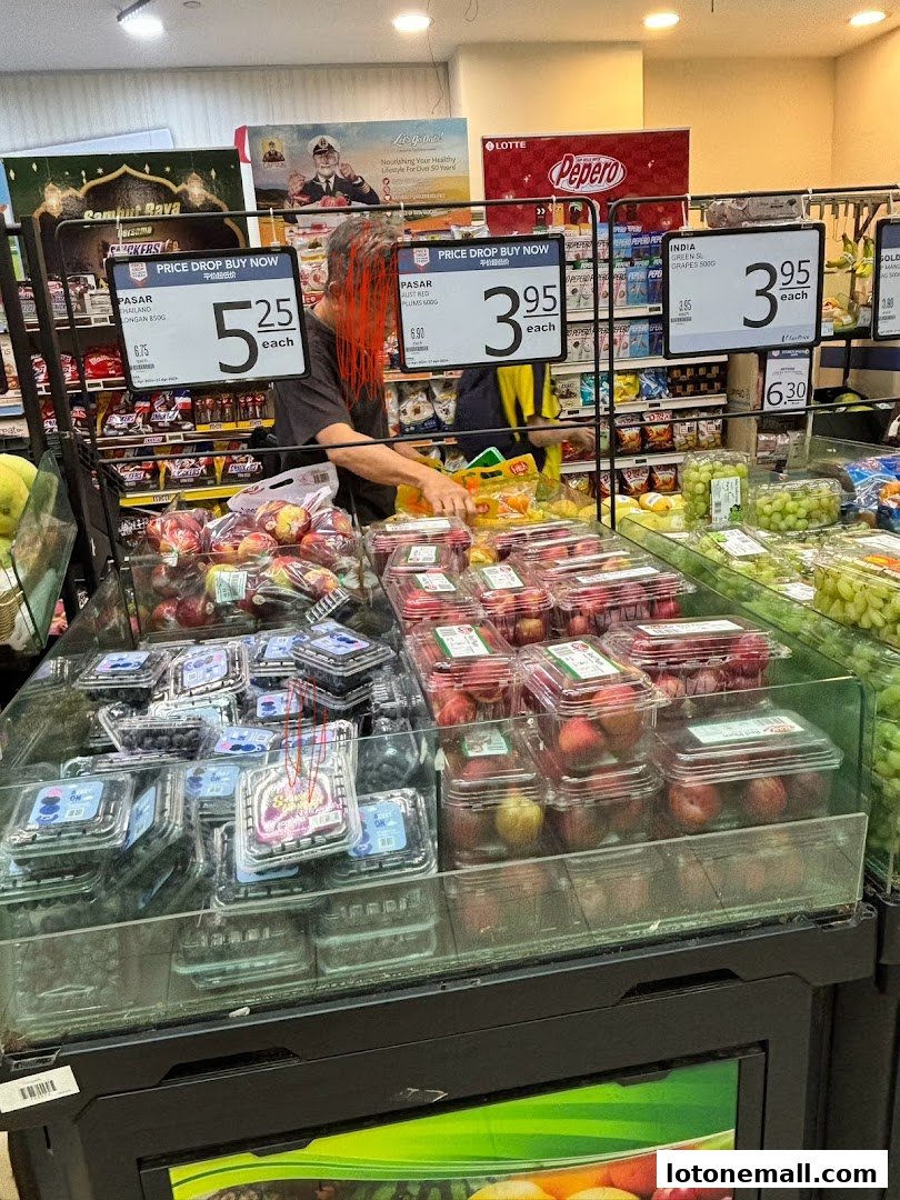 A display of fresh fruits like blueberries, apples, and grapes in a supermarket.