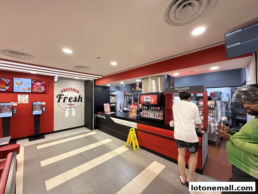 Interior view of a KFC restaurant with a counter, ordering kiosks, and customers.