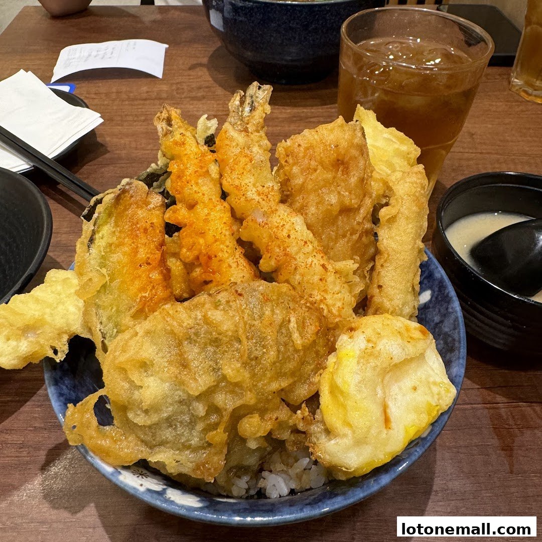 A close-up of a delicious tempura bowl with various fried items and a side of miso soup.