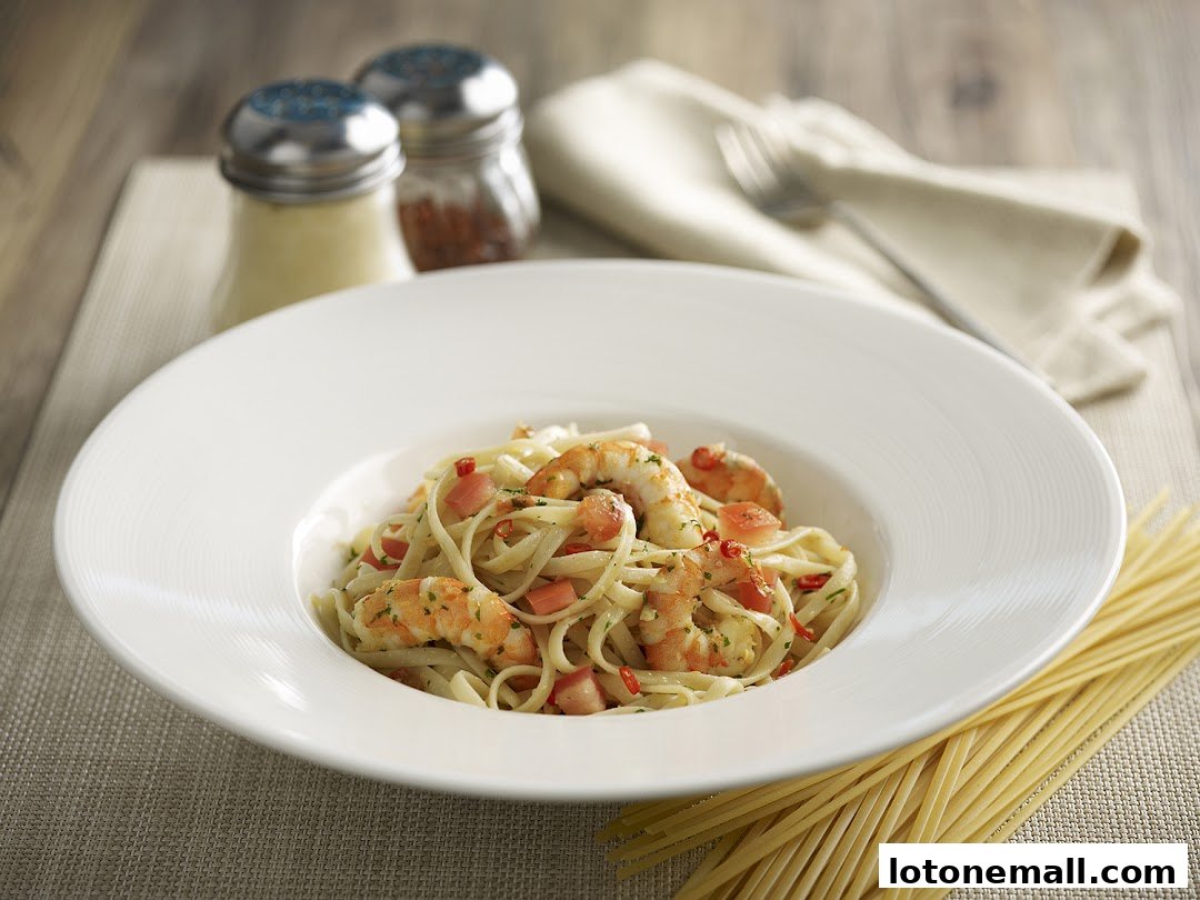 A close-up of a delicious shrimp pasta dish served in a white bowl with parmesan and chili flakes.