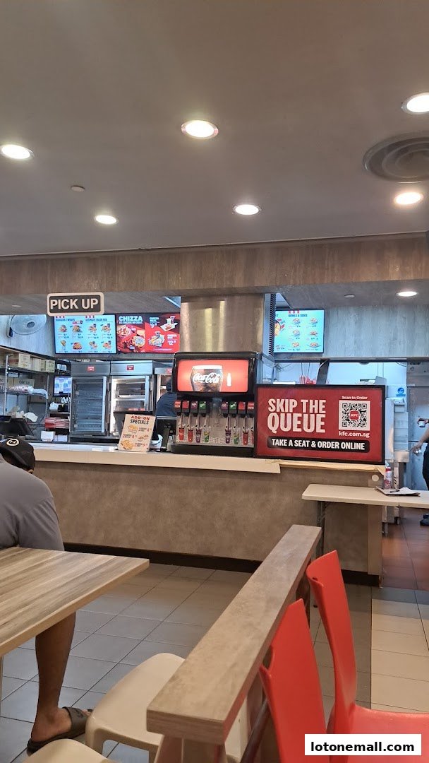 Interior view of a KFC restaurant showing the counter, drink station, and digital menus.