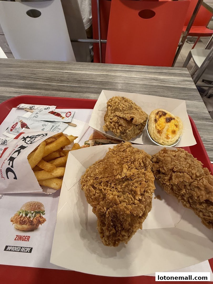 A tray of KFC fried chicken, fries, and an egg tart on a table.
