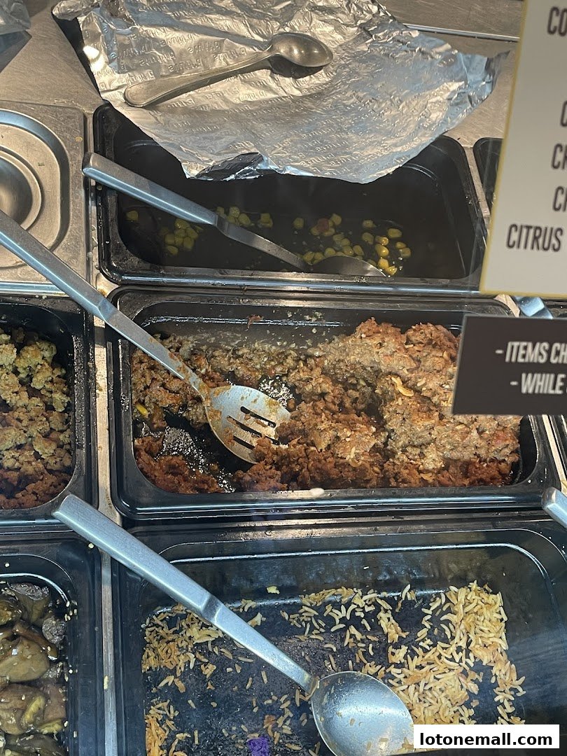 A close-up view of food service trays with various ingredients and serving utensils.