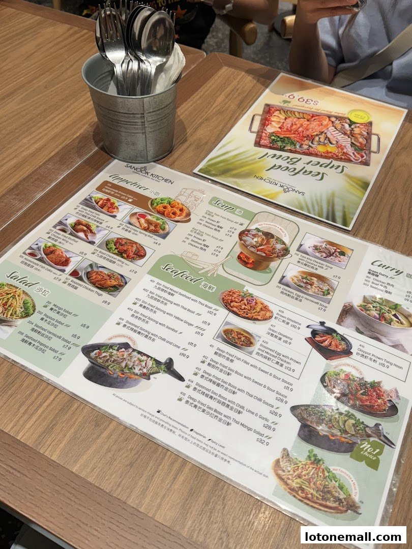 A table at Sanook Kitchen with menus and cutlery, showcasing various Thai dishes.