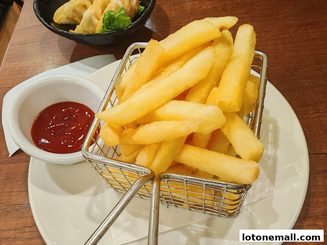 A basket of golden french fries served with ketchup and a side of dumplings.