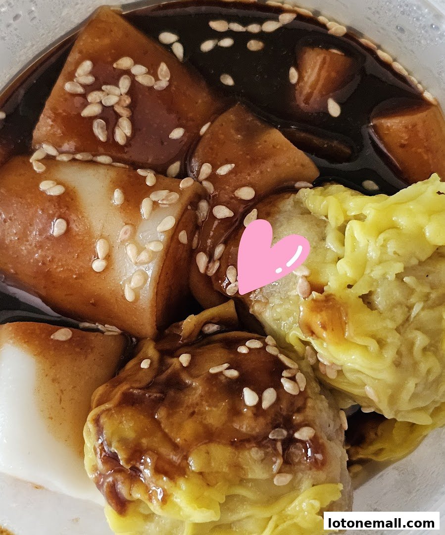 A close-up of delicious dim sum dishes with a sweet sauce and sesame seeds.