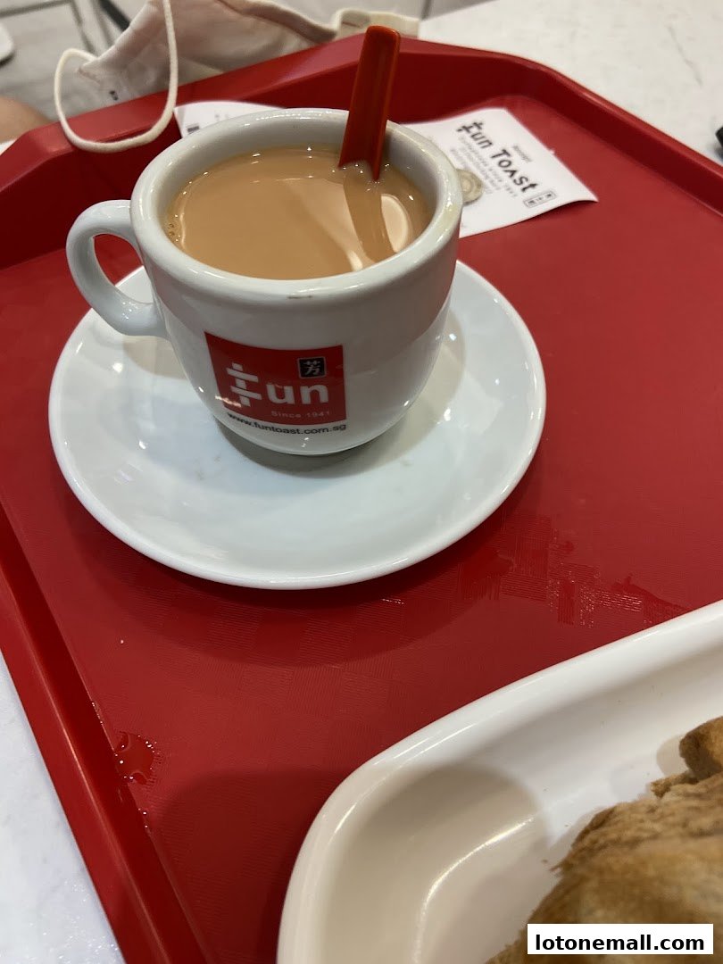 A cup of coffee with a red spoon on a red tray at Fun Toast.