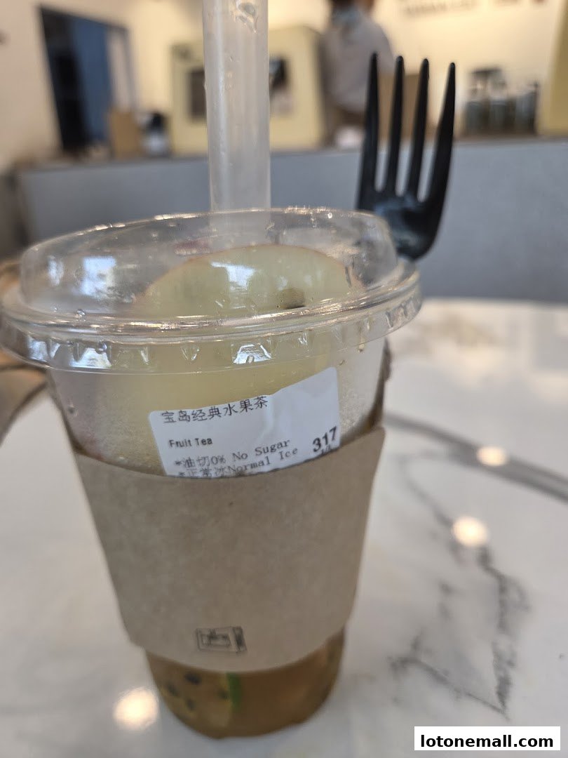 A close-up of a fruit tea with apple slices and a fork, showing customization options.