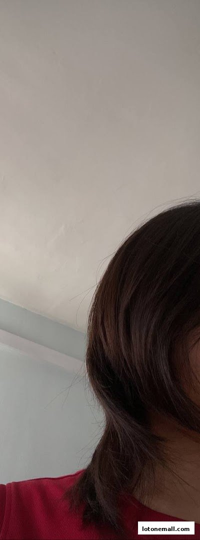 A close-up shot of a person's dark hair and shoulder wearing a red top.