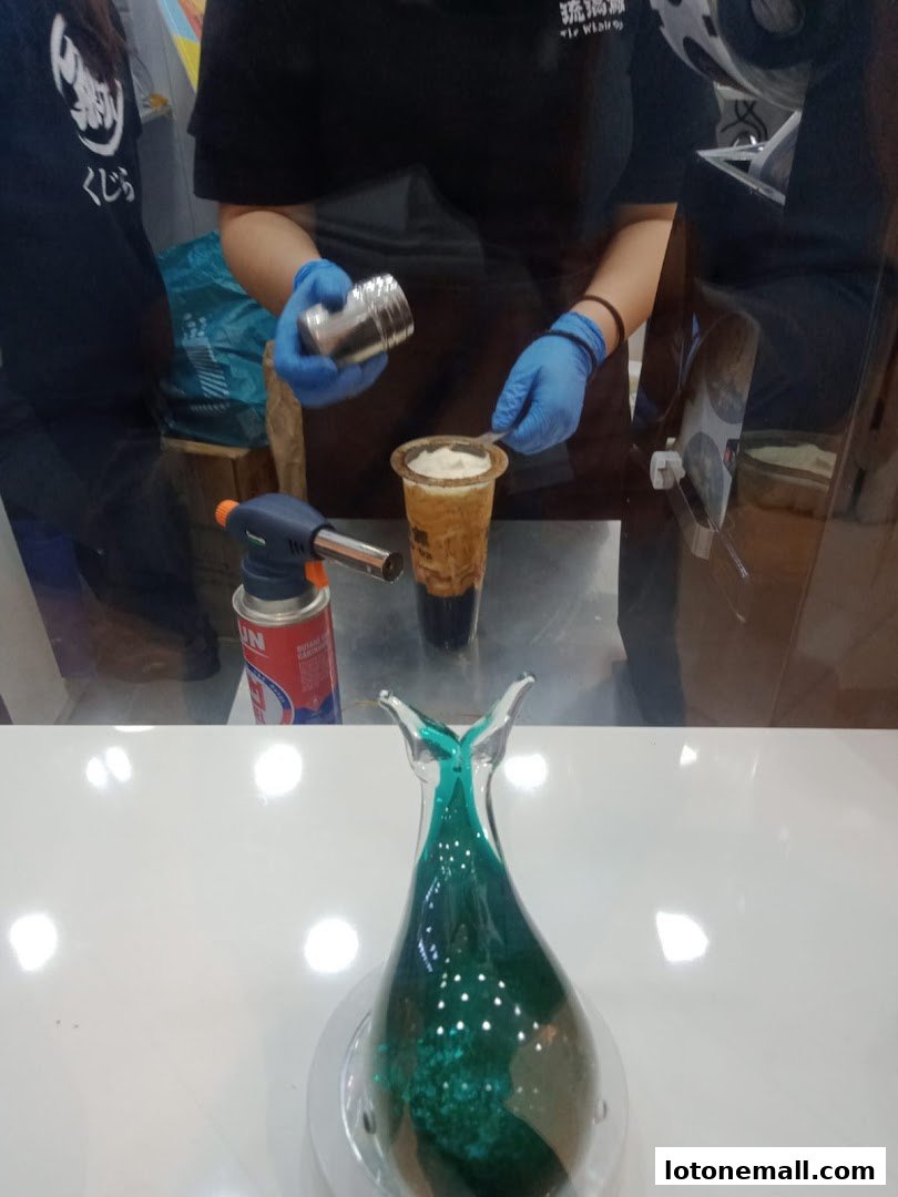 A barista prepares a drink with a torch and shaker at The Whale Tea.