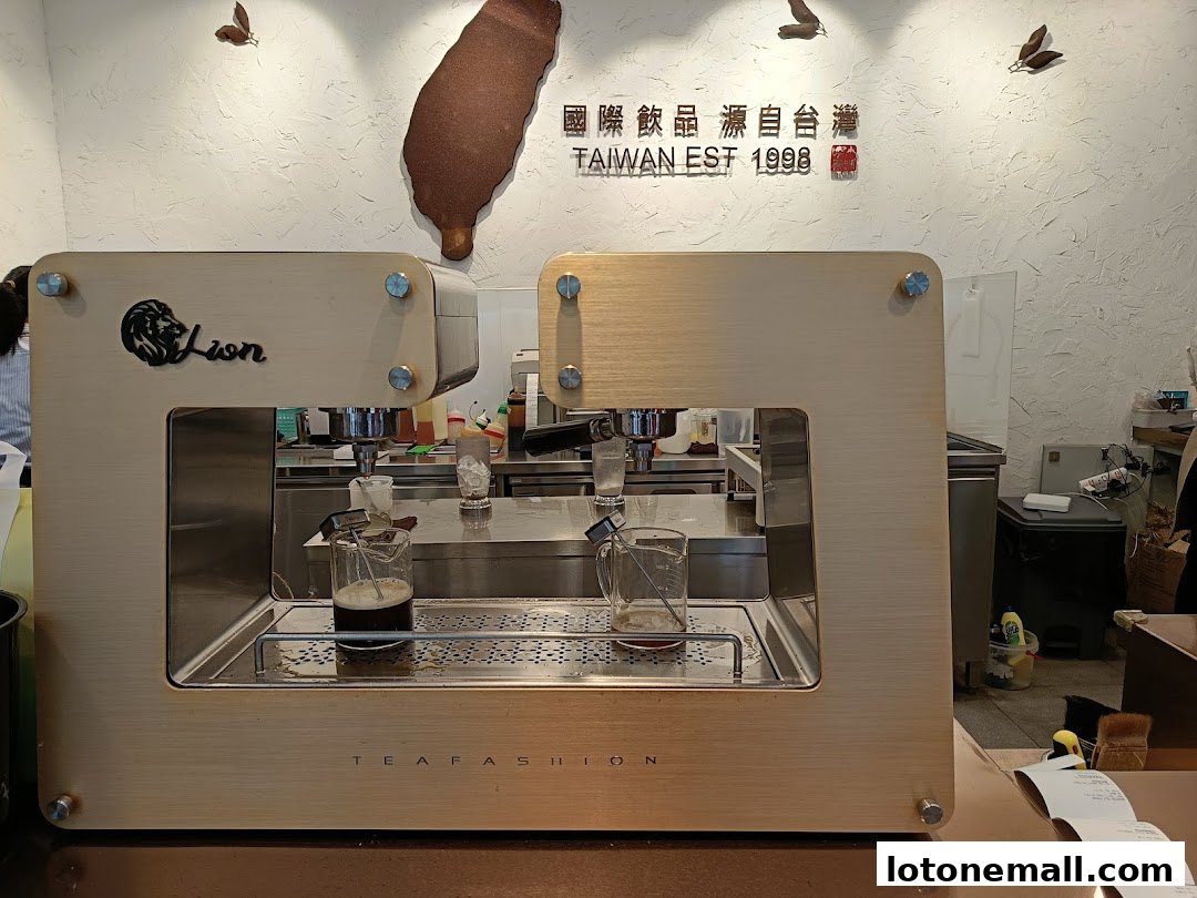A close-up of a modern, gold-colored tea brewing machine with two glasses of tea.