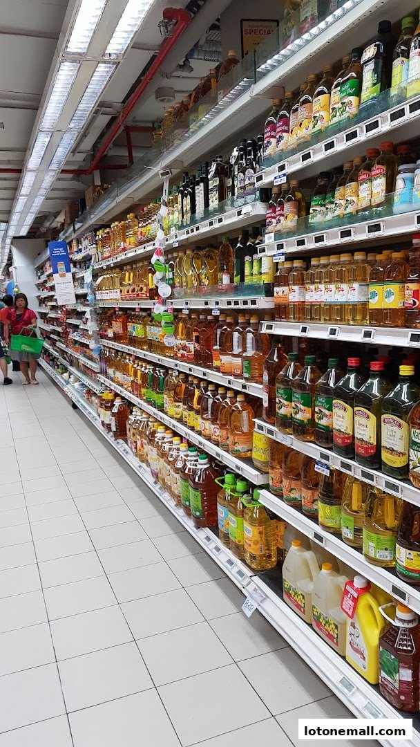 A wide aisle in a supermarket with shelves stocked with various cooking oils and condiments.