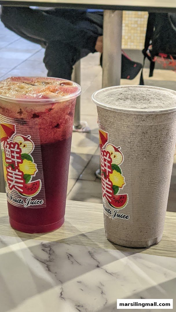 Two refreshing beverages, one red fruit juice and one grey smoothie, on a counter.