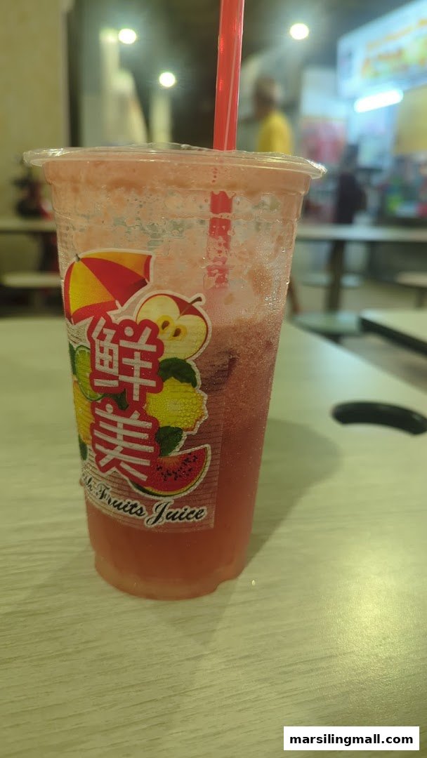 A refreshing red fruit juice drink in a plastic cup with a straw, featuring a colorful fruit label.