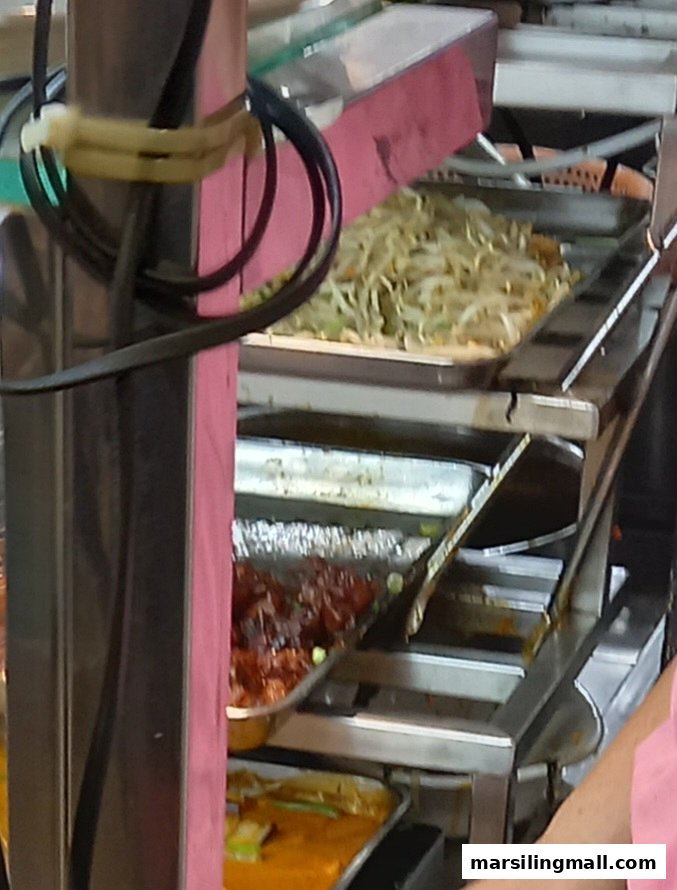 Close-up view of various cooked dishes, including stir-fried vegetables and meat, displayed in serving trays.
