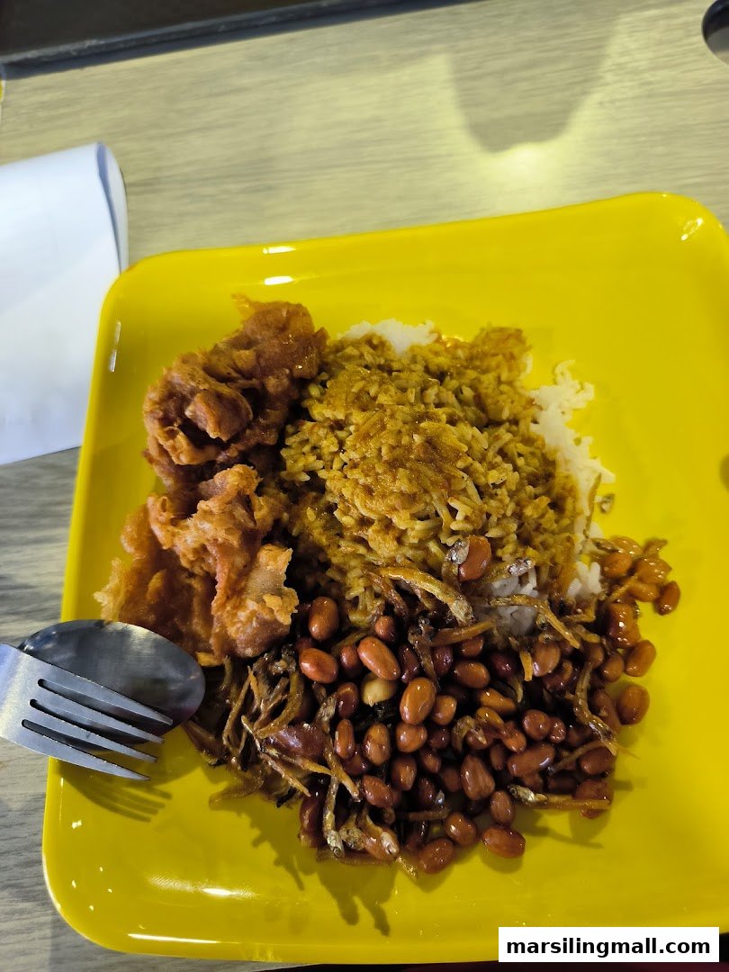 A vibrant yellow plate featuring a delicious serving of Nasi Lemak with fried chicken, peanuts, and anchovies.
