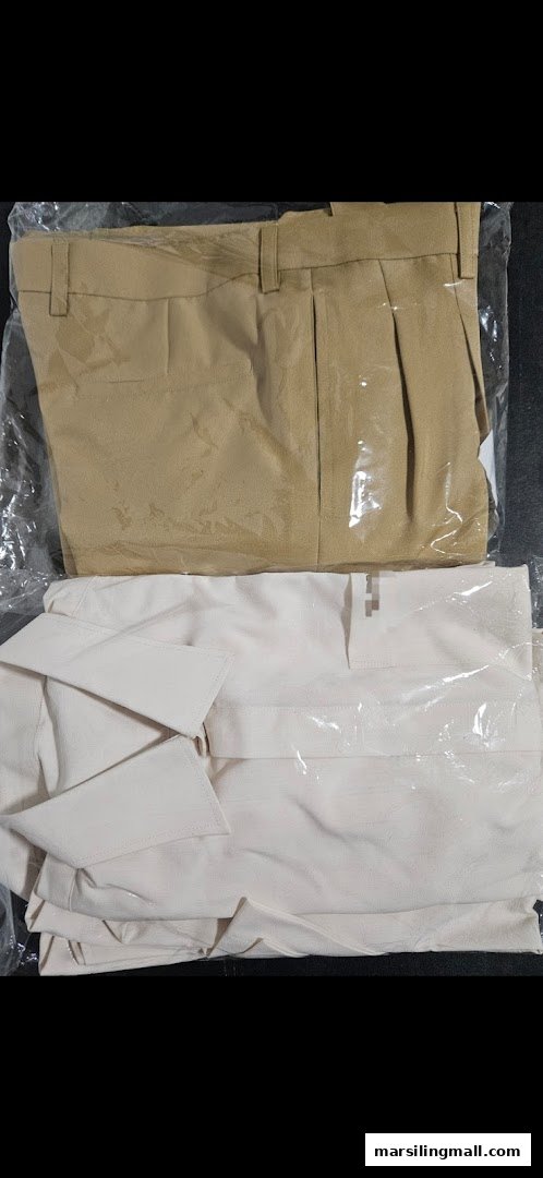 Two neatly packaged clothing items, light brown trousers and a white top, displayed on a dark surface.