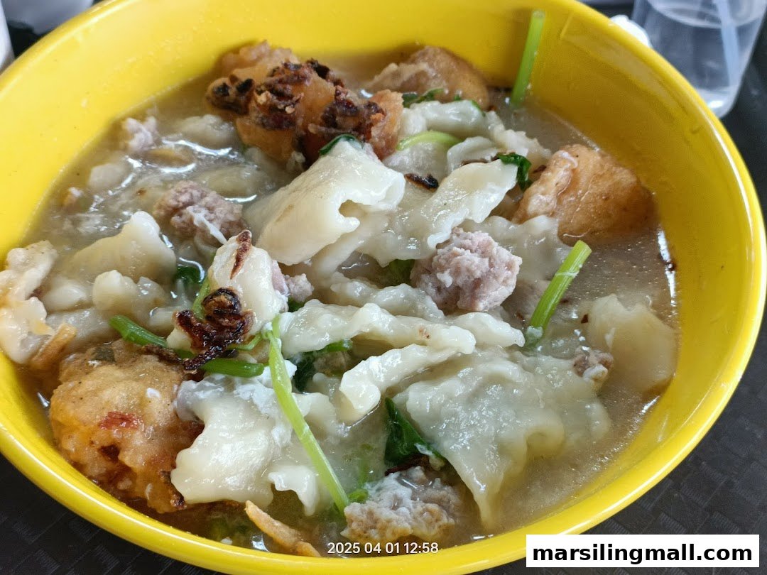 A close-up of a hearty bowl of handmade noodles with minced meat and fried ingredients in soup.