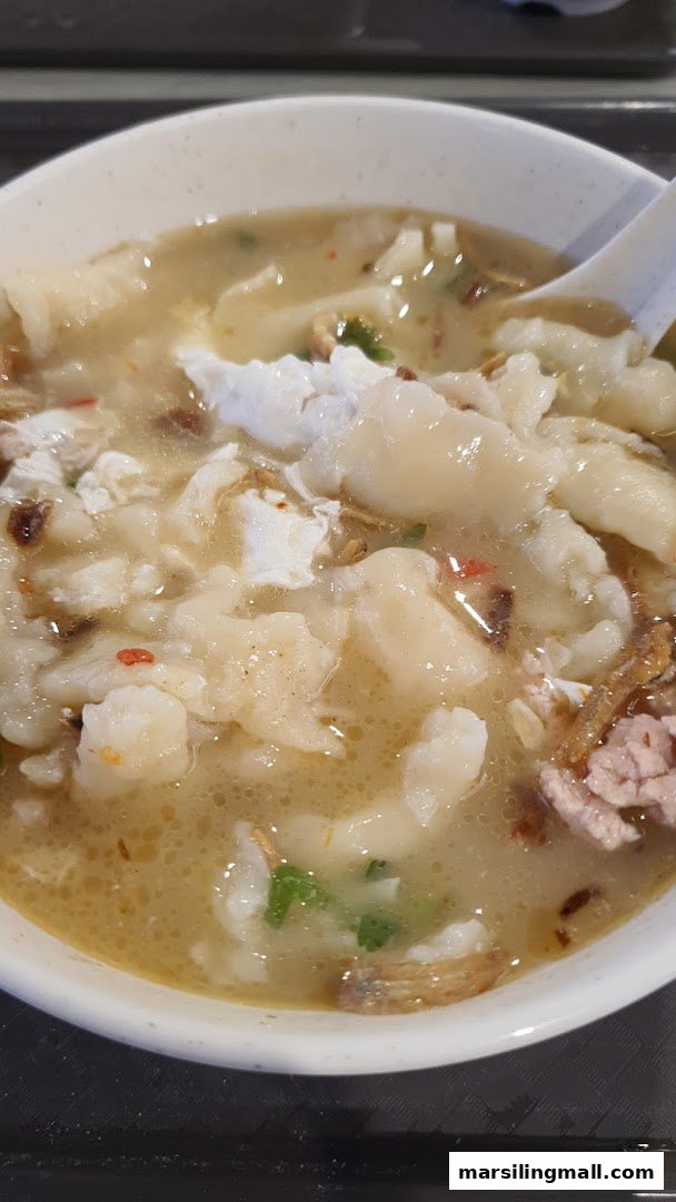 A close-up of a hearty bowl of Ah Yi Handmade Noodle Fish Soup, featuring tender noodles and rich broth.