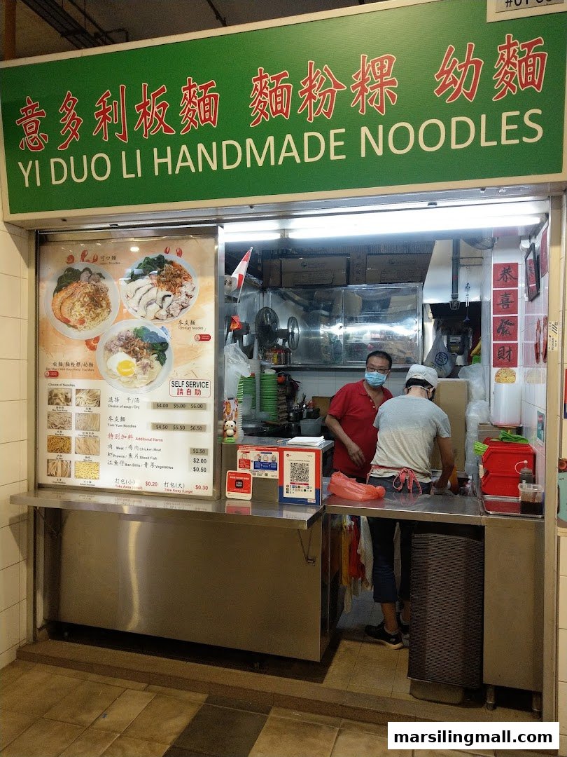 A hawker stall named Yi Duo Li Handmade Noodles with staff preparing food and a menu board.