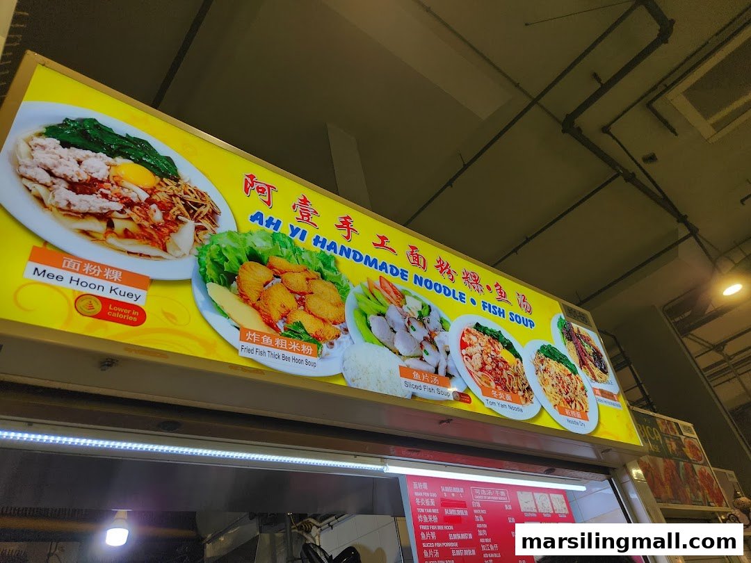 An illuminated signboard and menu board displaying various noodle and fish soup dishes with their names and prices.