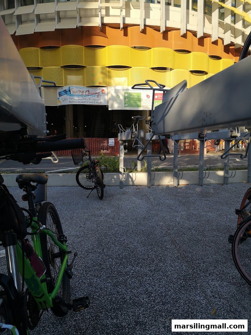 Exterior view of a building with a colorful facade, banners, and bicycles parked in the foreground.