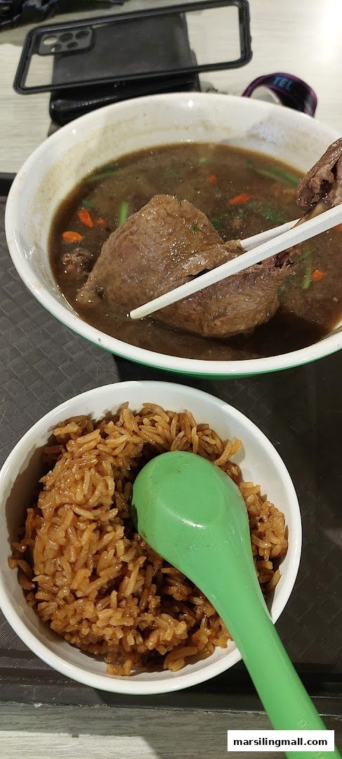A close-up of a delicious braised duck soup with rice, served with chopsticks and a spoon.