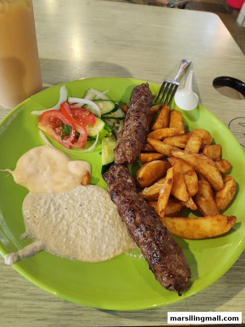 A vibrant plate featuring two kebabs, potato wedges, fresh salad, and sauces.