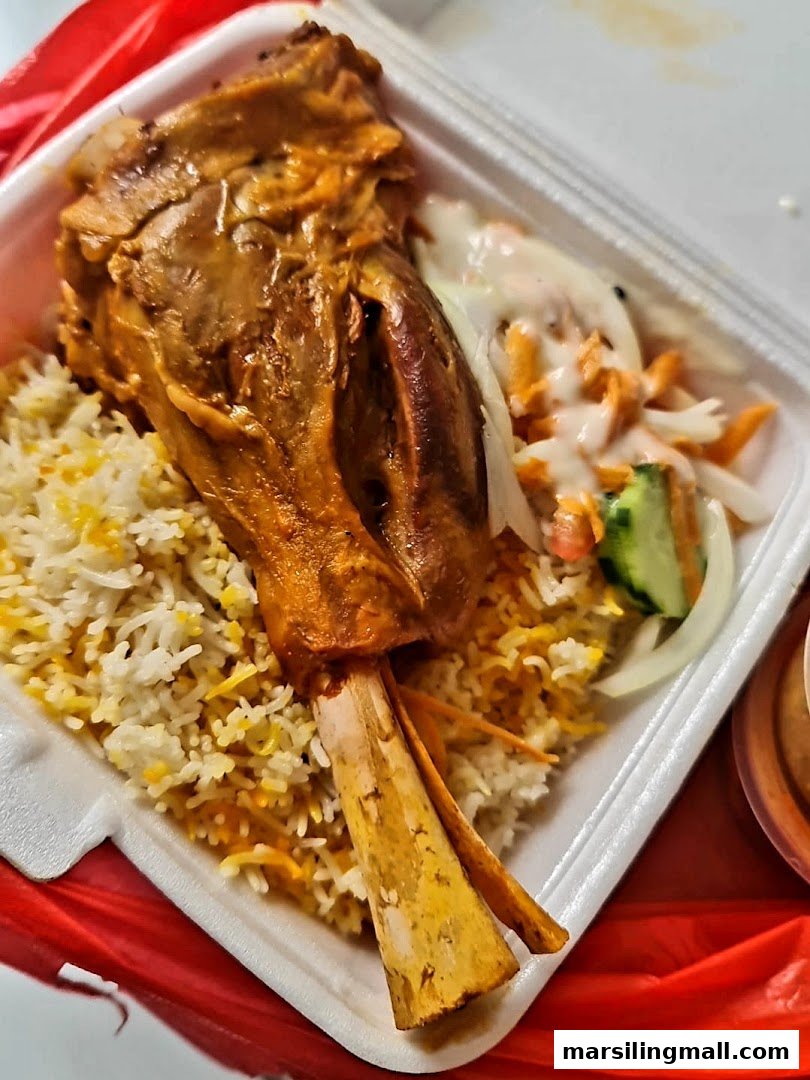 A delicious lamb shank with seasoned rice and fresh salad in a takeaway container.