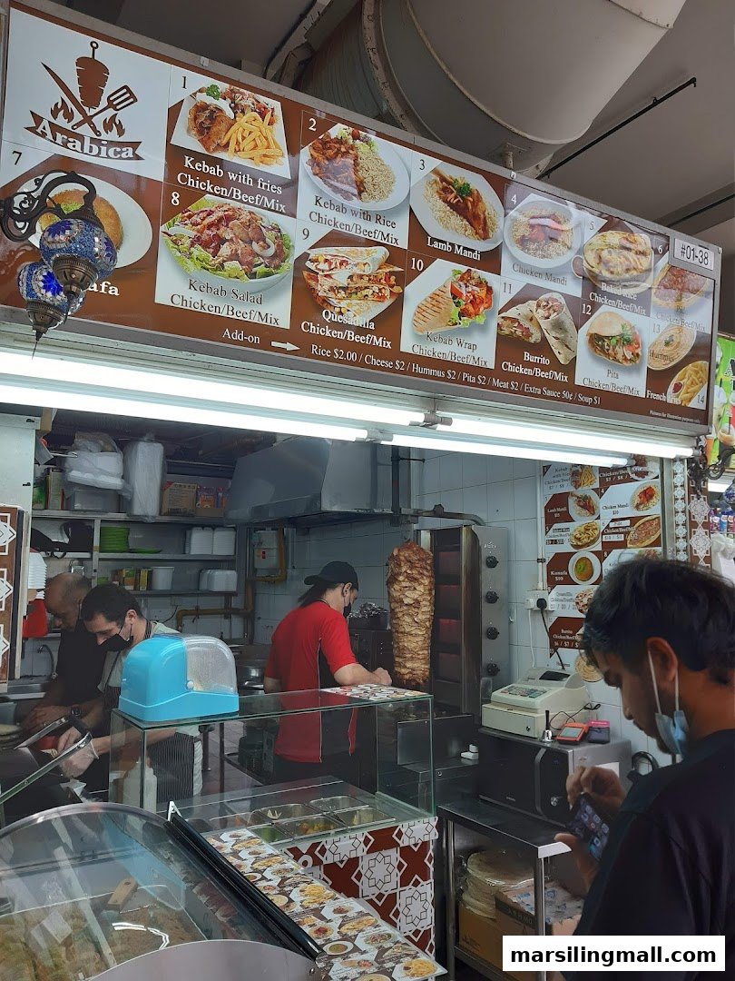 A vibrant food stall showcasing its extensive menu board and staff preparing fresh Middle Eastern cuisine.