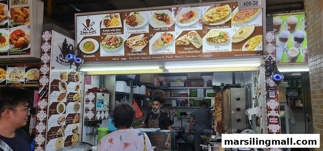 A bustling food stall named Arabica Kebab, featuring a large menu display and staff preparing food.