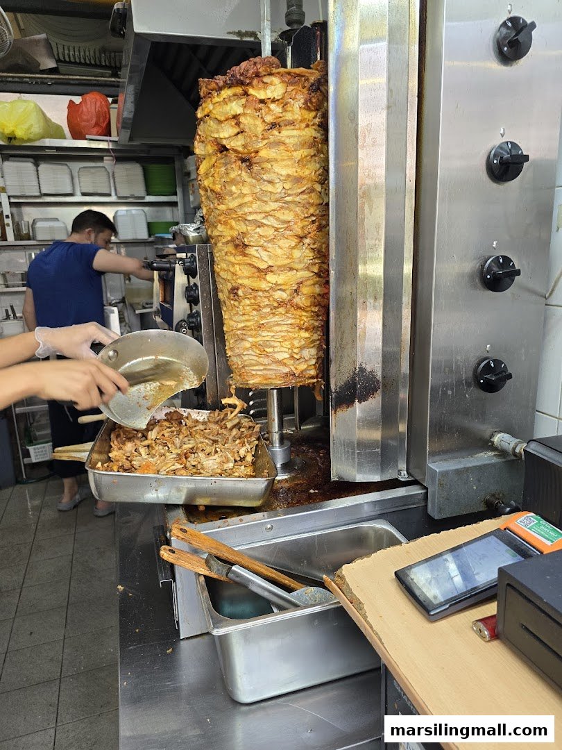 A large rotating kebab spit with freshly carved meat, ready for delicious meals at Arabica Kebab.