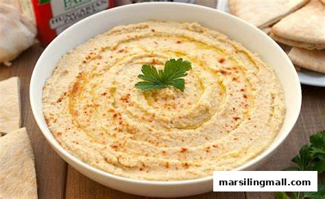 A bowl of creamy hummus garnished with paprika and parsley, served with pita bread.