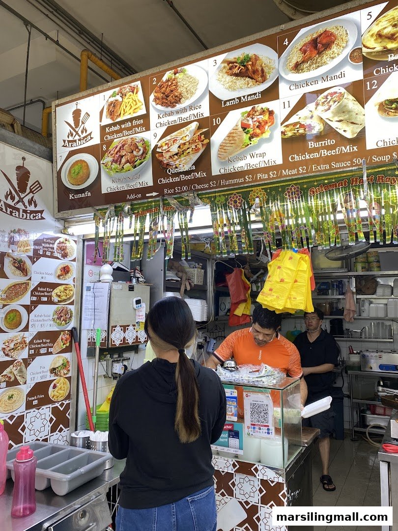 A vibrant image showcasing the menu board and counter of Arabica Kebab, with staff and a customer.