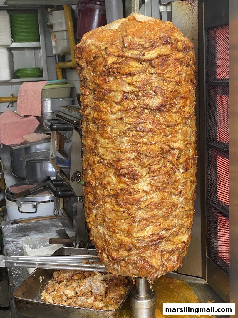 A large, golden-brown rotating skewer of seasoned meat for kebabs or shawarma.
