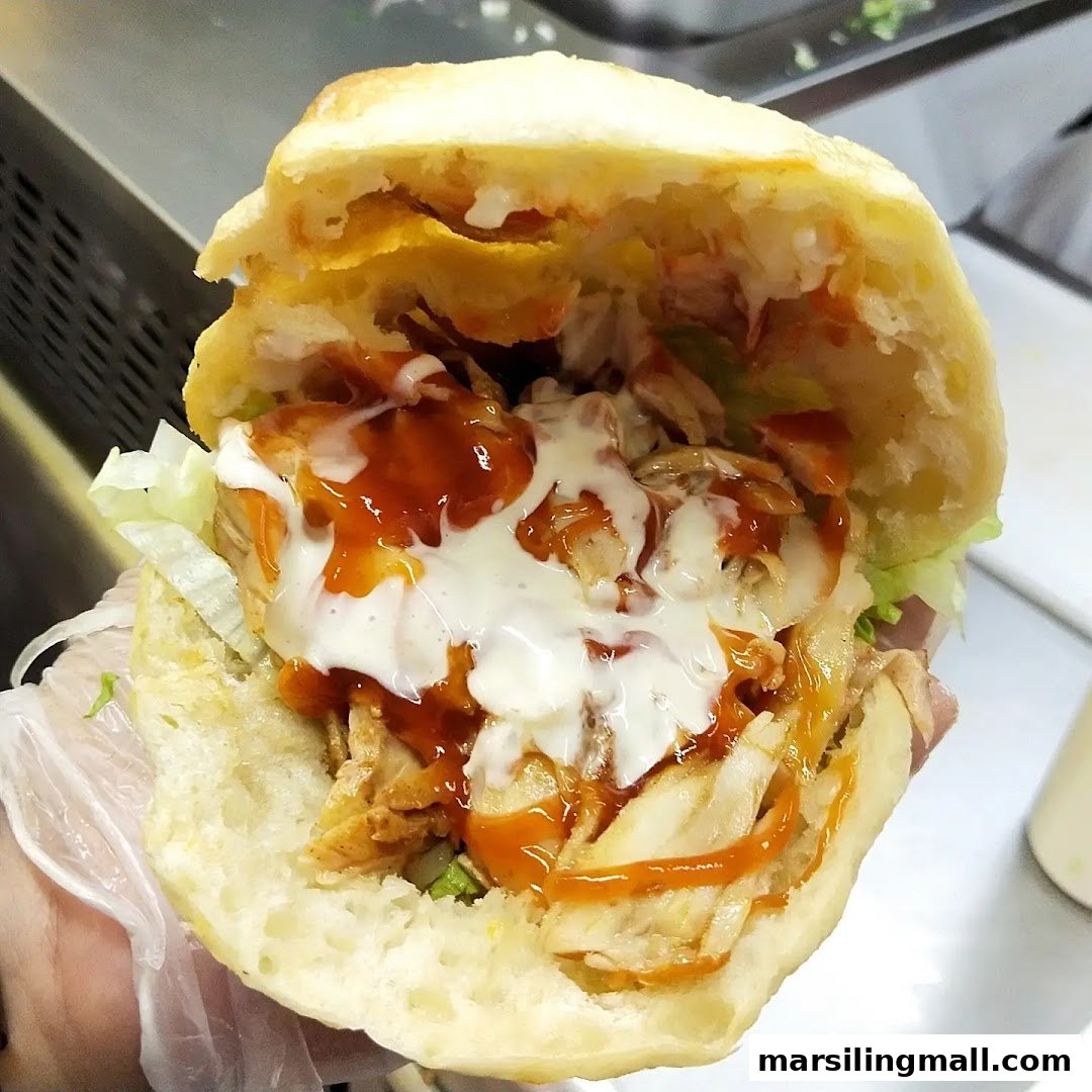 A close-up of a delicious kebab in pita bread, filled with meat, lettuce, and generous sauces.