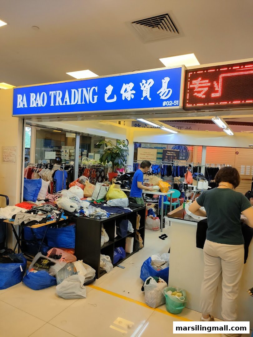 The entrance of Ba Bao Trading, a bustling clothing alteration and trading shop with merchandise and staff.