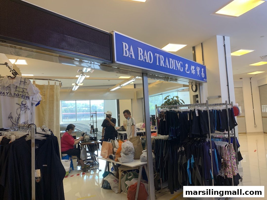 Interior view of Ba Bao Trading, showing clothing racks and a seamstress at work.